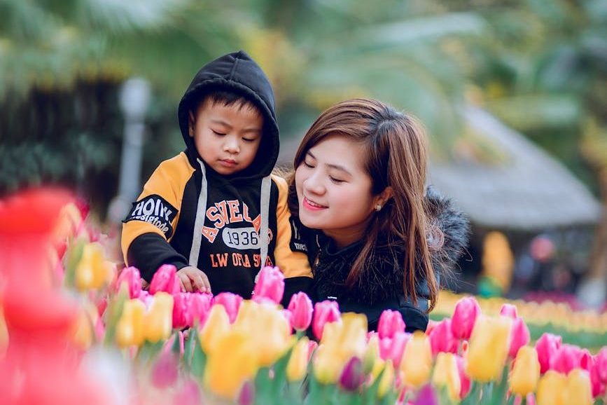selective focus photography of woman and toddler on flower bed
